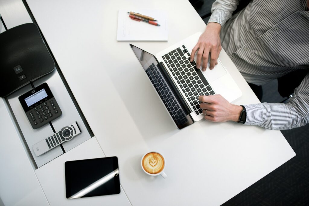 Person arbeitet an einem Laptop auf einem weißen Tisch