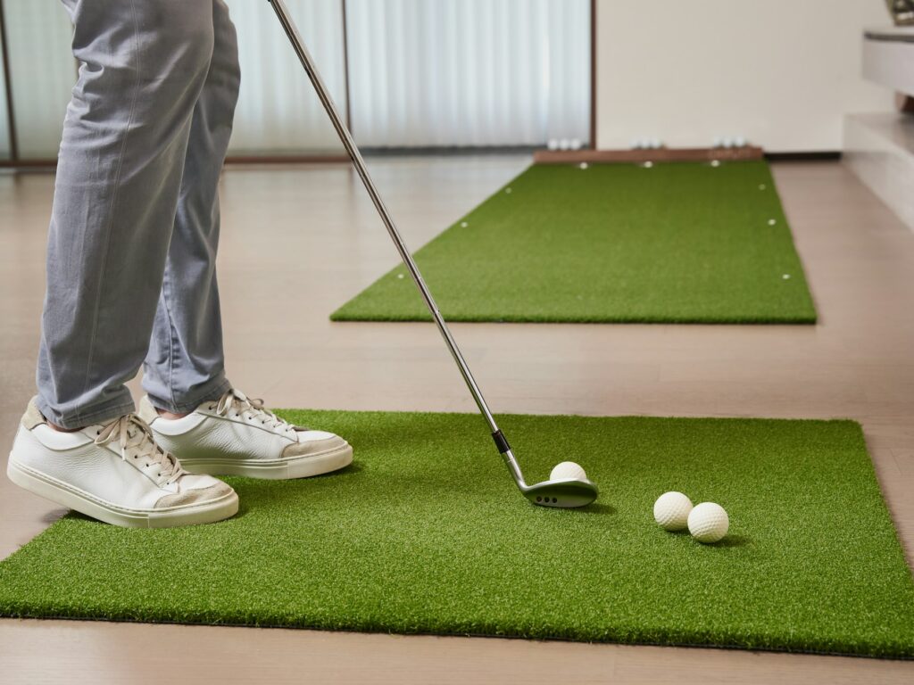 Golfer übt drinnen den Schwung auf einer Abschlagmatte